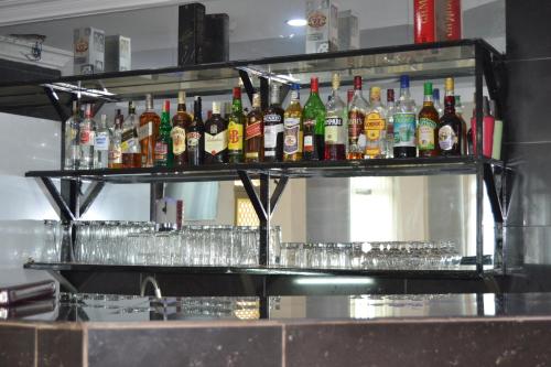 a shelf filled with bottles and glasses of alcohol at Massao Palace Hotel in Yaoundé