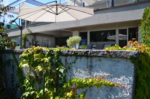 a stone wall with an umbrella in front of a house at Lakelodge Romanshorn in Romanshorn