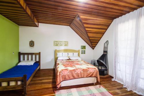 1 dormitorio con 2 camas y techo de madera en Casa do Esquilo Campos do Jordão Area Externa de 2000 m2, en Campos do Jordão