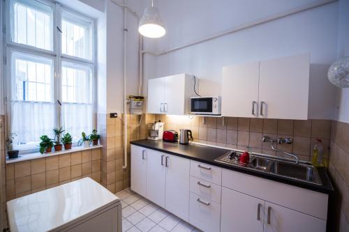 een keuken met witte kasten en een spoelbak bij Logement Sous le Château in Boedapest