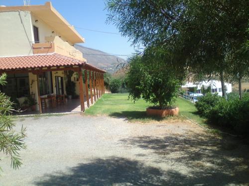 a house with a tree in front of a driveway at Zefyros Studios in Damnoni