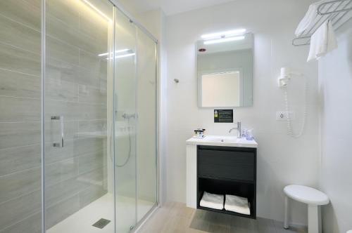 a bathroom with a glass shower and a sink at Hotel Alameda in Benidorm