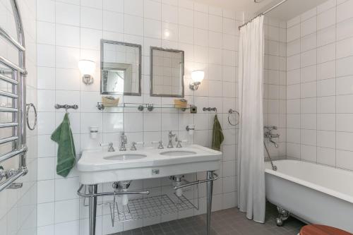 a white bathroom with a sink and a bath tub at Storebro Herrgård in Vimmerby