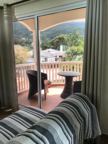 a living room with a view of a balcony at Flower Garden Self-Catering Apartments in Beau Vallon