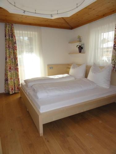 a large white bed in a room with windows at TUX DIAMANT in Tux