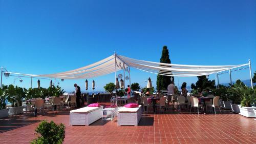 a patio with tables and chairs and a white canopy at Hotel Continental in Taormina