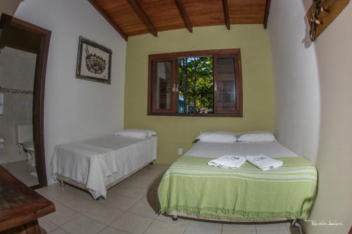 a bedroom with two beds and a window at Pousada Villa Prainha in Farol de Santa Marta