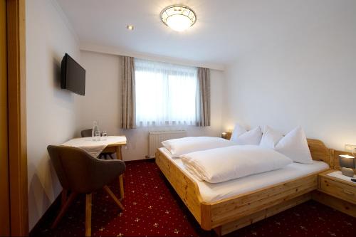 a bedroom with a bed with a desk and a chair at Pension Edelweiß in Sankt Johann im Pongau