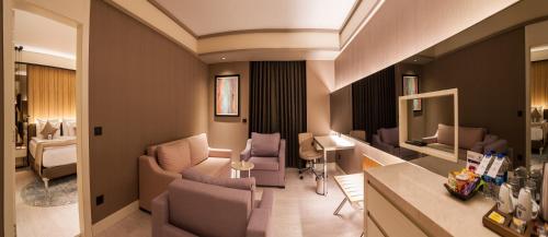 uma sala de estar com um sofá e cadeiras e um quarto em Bayır Diamond Hotel & Convention Center Konya em Konya