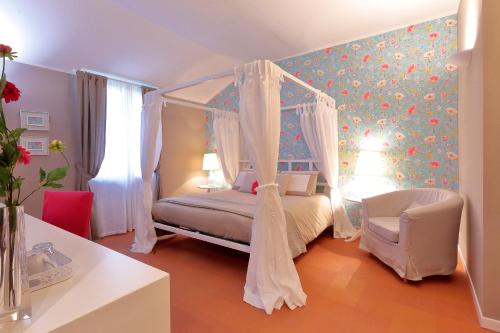 a bedroom with a canopy bed and a chair at Agriturismo Tenuta "Il Cigno" in Villanterio