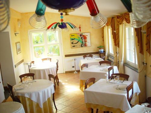 a restaurant with white tables and chairs and windows at Locanda Miranda in Tellaro