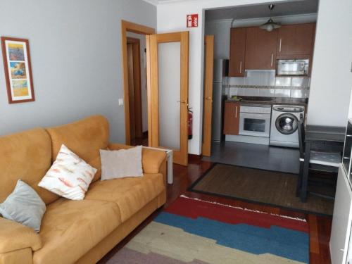 a living room with a couch and a kitchen at Iradri, Apartamento Playa Gijón in Gijón
