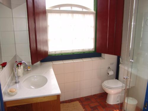 a bathroom with a sink and a toilet and a window at Casa no Centro Histórico com 3 Quartos in Paraty