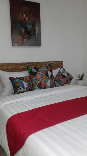 a bed with a red and white blanket and pillows at Anugrah Jaya Guest House in Canggu