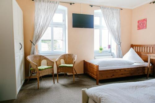 a bedroom with a bed and two chairs and a table at Landhotel Airport-Inn in Lautzenhausen
