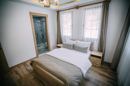Schlafzimmer mit einem Bett mit weißer Bettwäsche und Kissen in der Unterkunft Nova Uzungöl in Uzungöl