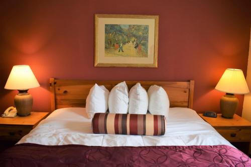 a bedroom with a bed with white pillows and two lamps at Baymont by Wyndham Wichita East in Wichita