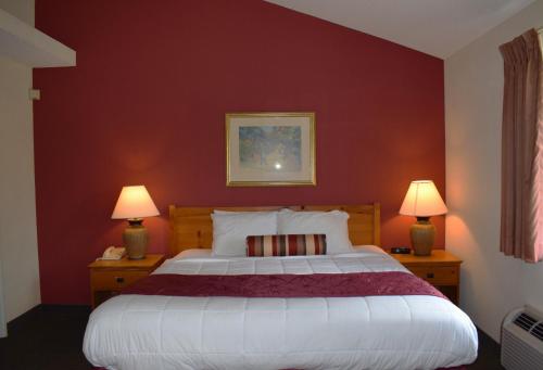 um quarto com uma cama grande e paredes vermelhas em Baymont by Wyndham Wichita East em Wichita
