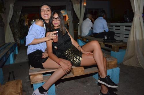 two young women sitting on a wooden bench at Ostello Salento in Alezio