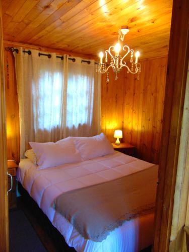 a bedroom with a bed with a chandelier at Cabañas Puente Negro in Puente Negro