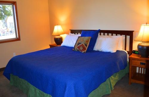 a bedroom with a blue bed with pillows and two lamps at Montecito Sequoia Lodge in Sequoia National Park