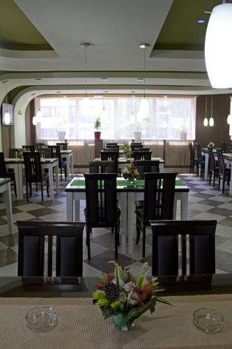 クラグイェヴァツにあるGarni Hotel Tri Oのダイニングルーム(テーブル、椅子、花のテーブル付)