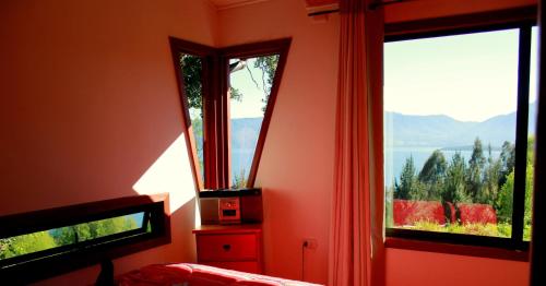 a bedroom with two windows with a view of the mountains at Cabañas Ayalén con vista al Lago in Pucón