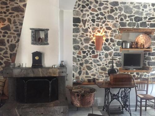 a living room with a fireplace and a stone wall at Stephania's Stone House in Karyes