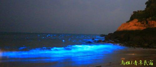 a beach at night with blue lights in the water at Matsu 1st Hostel in Nangan