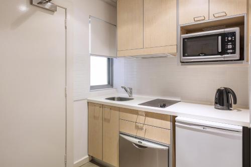 a small kitchen with a sink and a microwave at Oaks Broome Hotel in Broome