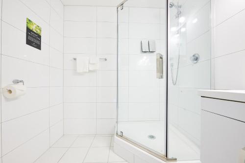 a white bathroom with a shower and a sink at Mount Richmond Hotel in Auckland