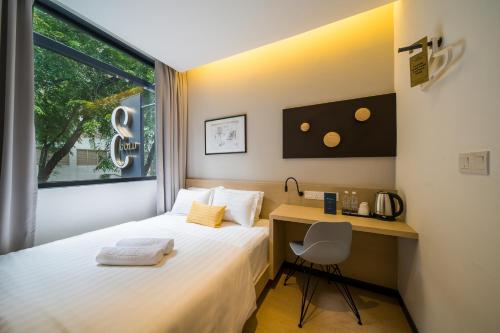 a bedroom with a bed and a desk and a window at Gold3 Boutique Hotel in Kuala Lumpur