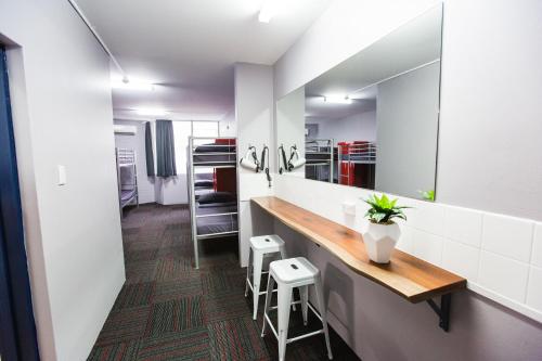 a bathroom with a vanity with a mirror and stools at Mad Monkey Waterfront in Cairns
