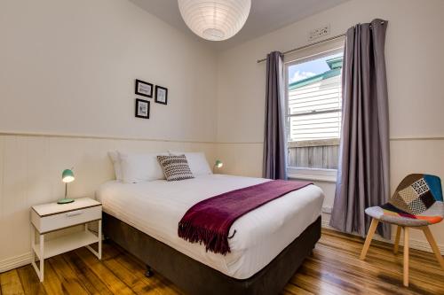 Un dormitorio con una cama grande y una ventana en Rosehaven Cottage, en Hobart