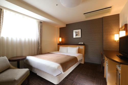 札幌市にあるホテル法華クラブ札幌のベッドとテレビが備わるホテルルームです。