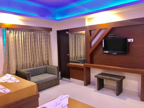 een hotelkamer met een tv en een bed en een bank bij Hotel Grand Suites in Bangalore