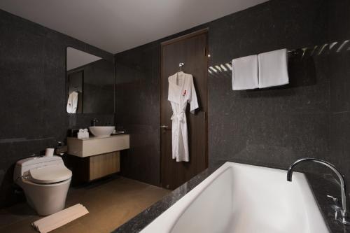 a bathroom with a bath tub and a toilet at Swiss-Belinn Luwuk in Luwuk
