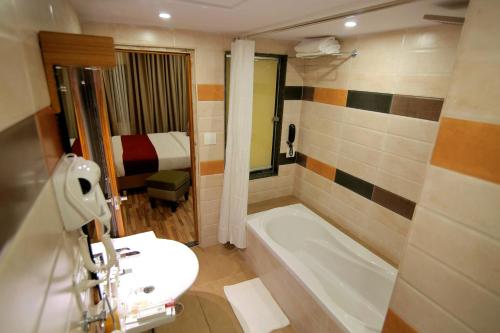 a bathroom with a sink and a tub and a toilet at Hotel Hampi International in Hospet