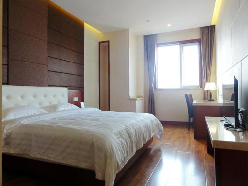 a bedroom with a bed and a desk and a television at Hua Qi Kaiserdom Hotel Zhongshan Road St Michael's Cathedral and Zhanqiao Pier Qingdao in Qingdao