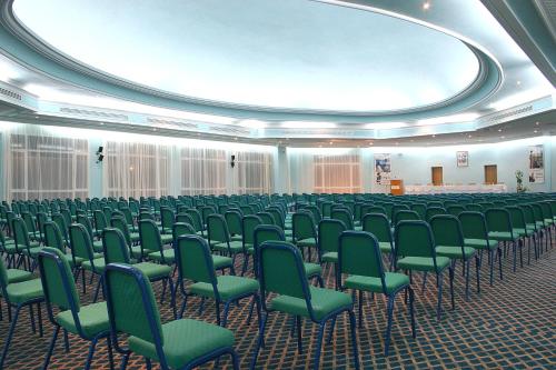 a large room filled with green chairs and a stage at El Mouradi Mahdia in Mahdia