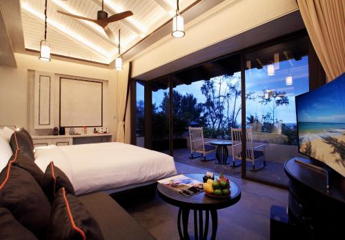 a bedroom with a bed and a table with a bowl of fruit at Baba Beach Club Natai Luxury Pool Villa Hotel by Sri panwa - SHA Plus in Natai Beach
