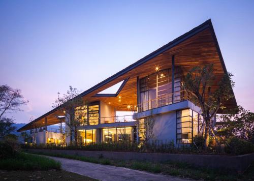 a large house with a wooden facade at night at Gliding Villa in Khao Yai in Mu Si