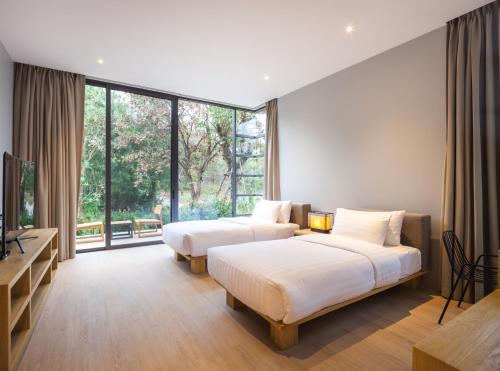 two beds in a room with large windows at Gliding Villa in Khao Yai in Mu Si