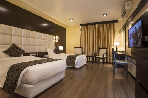 a hotel room with two beds and a flat screen tv at United Business Hotel in Kathmandu