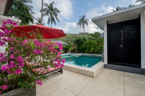 a swimming pool with a red umbrella and purple flowers at Dream Estate Resort in Senggigi 