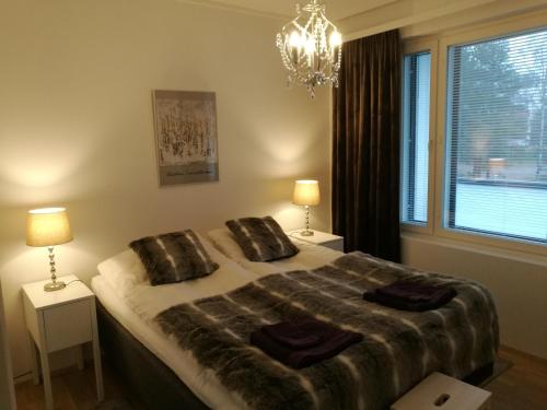 a bedroom with a bed with two lamps and a window at RovaVisit Apartments Siljo in Rovaniemi