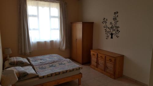 ein Schlafzimmer mit einem Bett, einer Kommode und einem Fenster in der Unterkunft Gut Richthofen in Swakopmund
