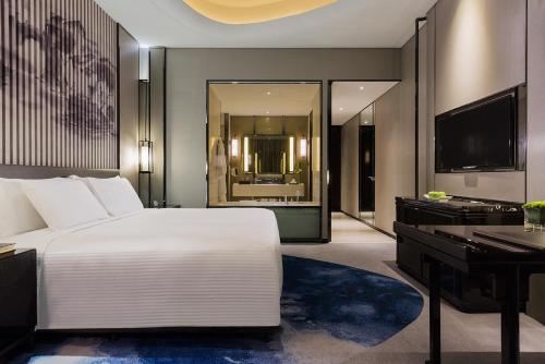 a bedroom with a large white bed and a desk at Wanda Realm Hotel Wuhu in Wuhu