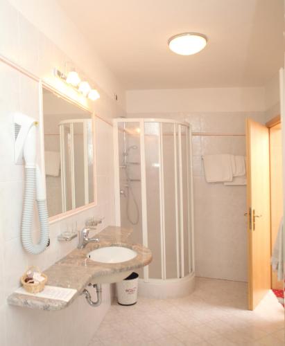 a bathroom with a sink and a shower at Naturhotel Waldheim in Anterivo
