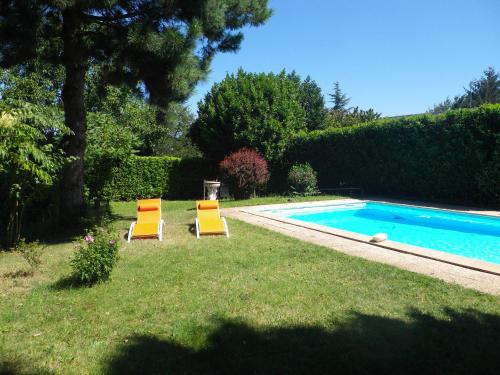 two chairs sitting in the grass next to a swimming pool at Chambres d'Hôtes Mado et Lulu in Collonges-au-Mont-dʼOr